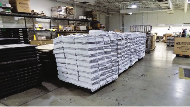 Pallets of printed papers wait to be stitched and trimmed into booklets. Using the correct paper size saves both money and effort in the final stitching process.